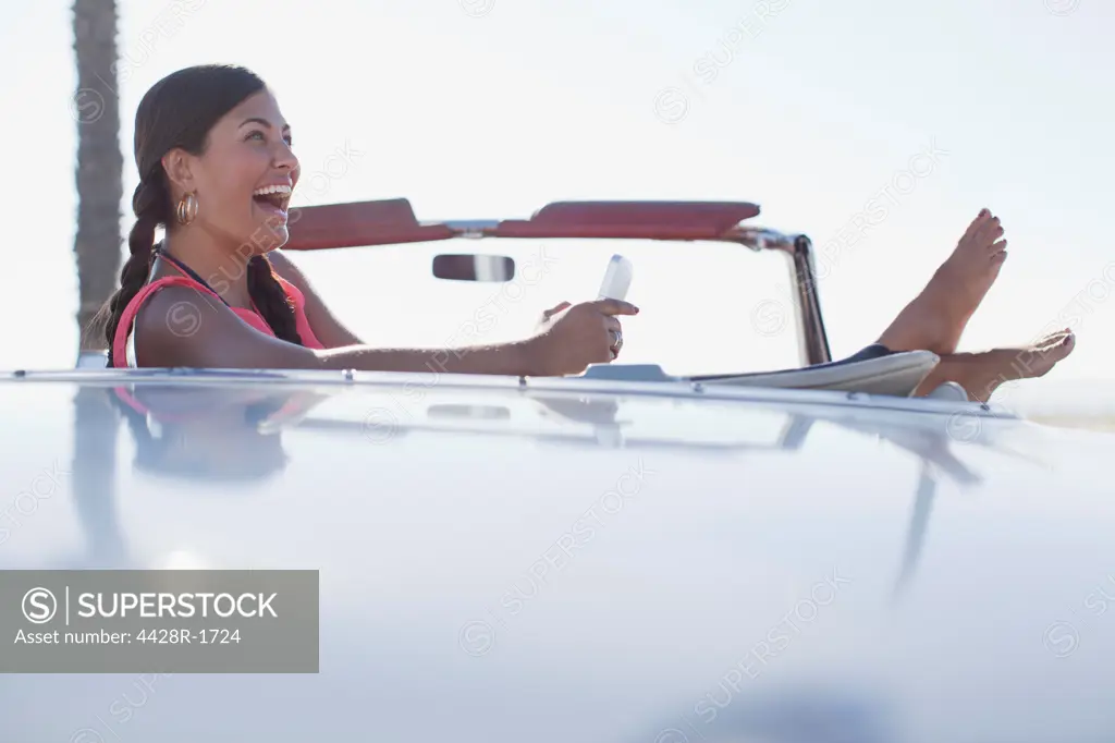Los Angeles, USA, Laughing girl using cell phone in convertible