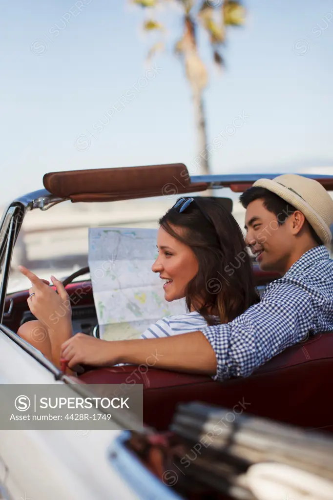 Los Angeles, USA, Smiling couple reading road map convertible