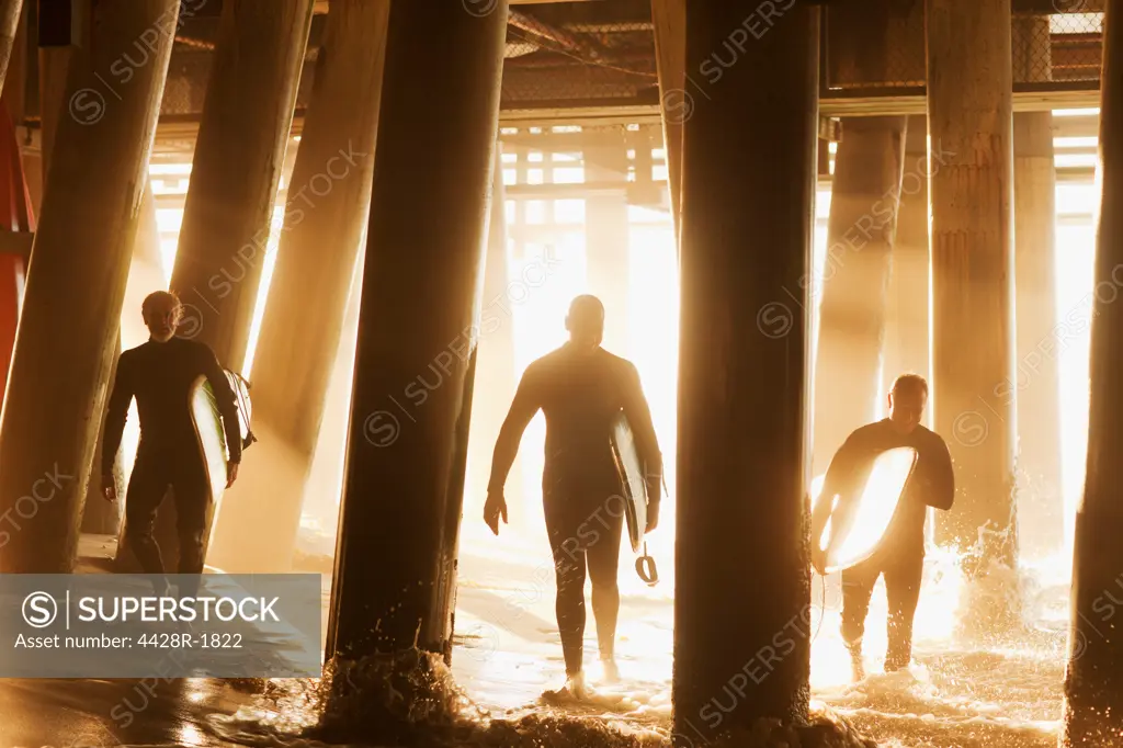 Los Angeles, USA, Surfers carrying boards under pier