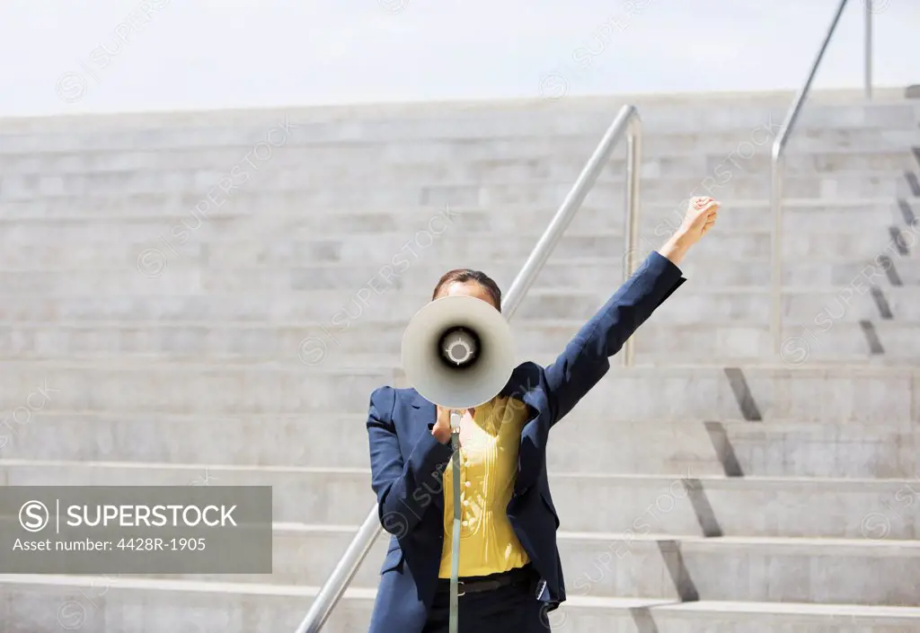 Spain, Businesswoman using megaphone on urban steps