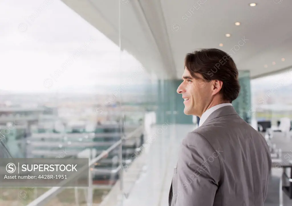 Spain, Smiling businessman looking out window of conference room