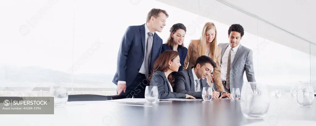 Spain, Business people watching businessman sign contract in conference room