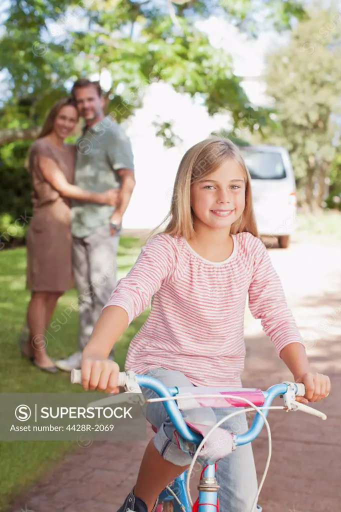 Cape Town, South Africa, Portrait of smiling girl on bicycle with parents in background