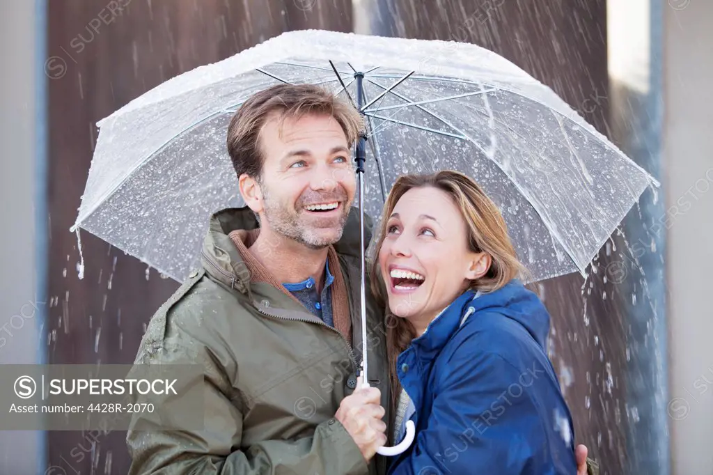 Cape Town, South Africa, Happy couple under umbrella in downpour