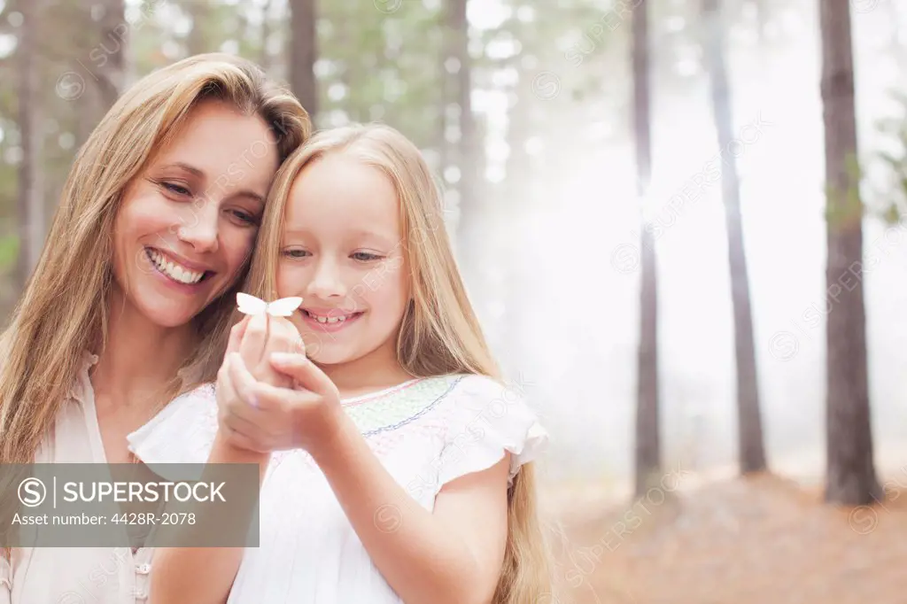 Cape Town, South Africa, Smiling mother and daughter holding butterfly in woods