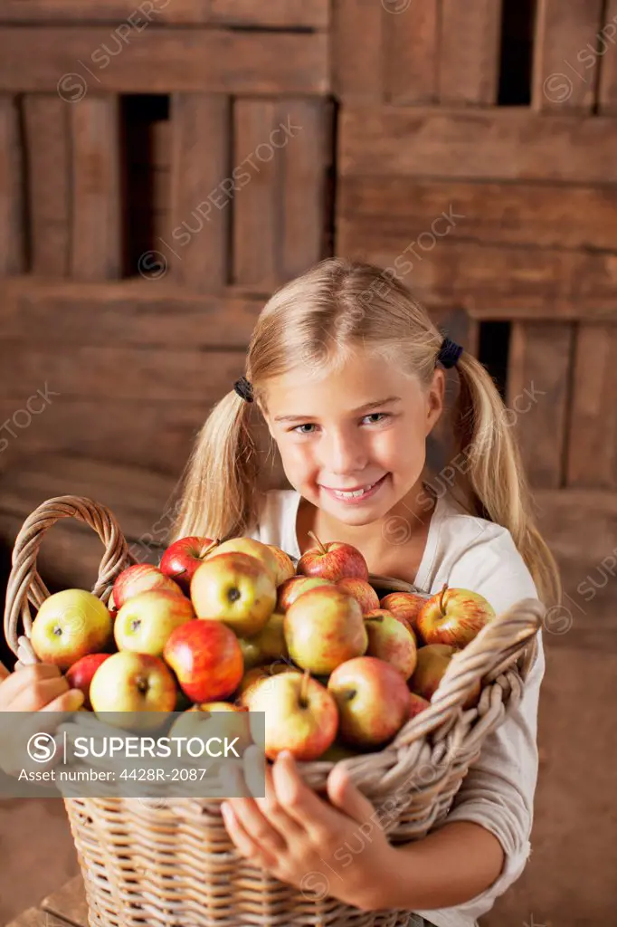 Cape Town, South Africa, Portrait of smiling girl holding bushel of apples