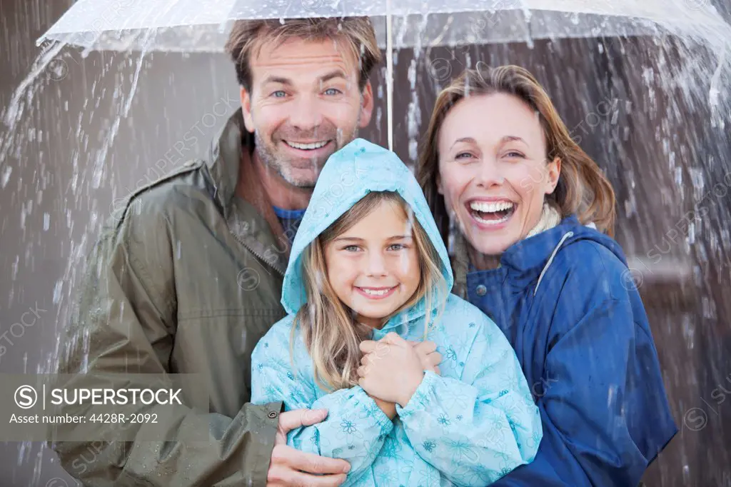 Cape Town, South Africa, Portrait of enthusiastic family under umbrella in downpour