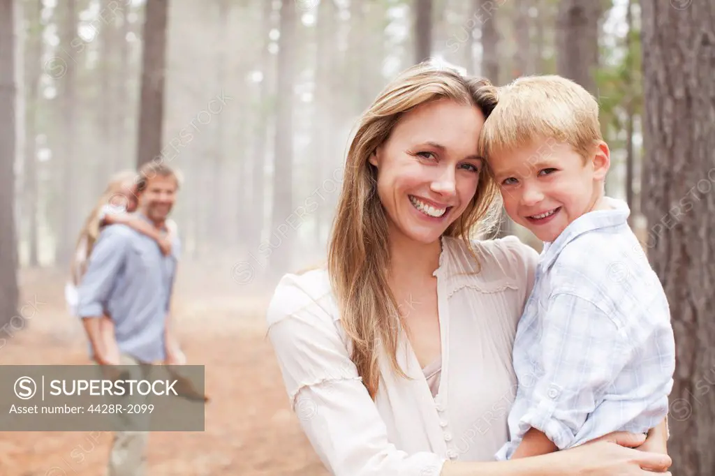 Cape Town, South Africa, Portrait of smiling mother holding son in woods