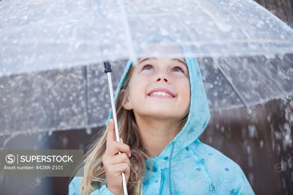 Cape Town, South Africa, Close up of smiling girl under umbrella in downpour