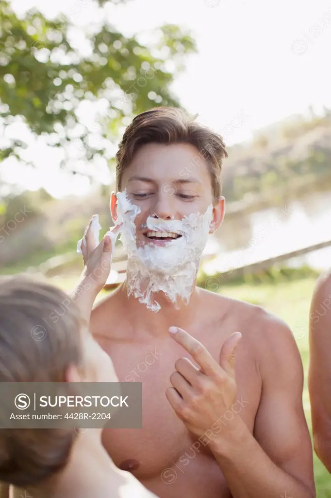 Cape Town, Son helping father apply shaving cream to face at lakeside