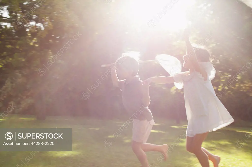 Cape Town, Boy and girl holding hands and running with butterfly nets in grass