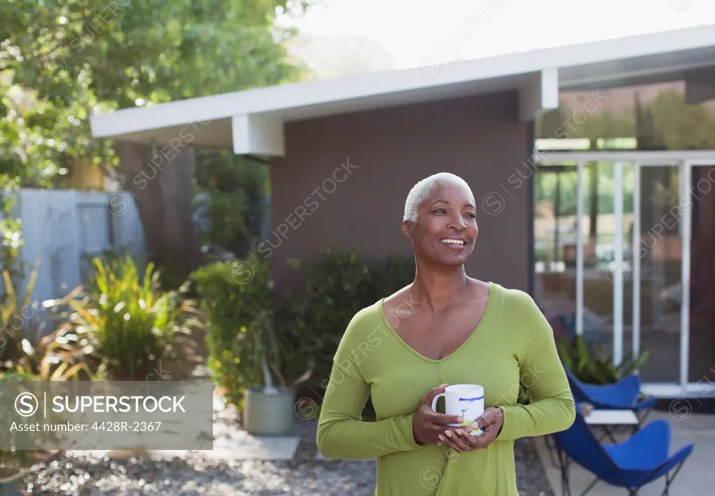 Los Angeles, USA, Older woman having cup of coffee in backyard