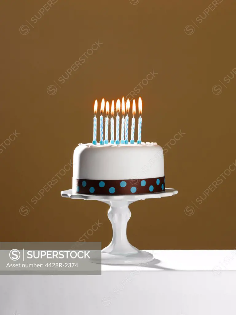 Birthday cake with lit candles on cake stand