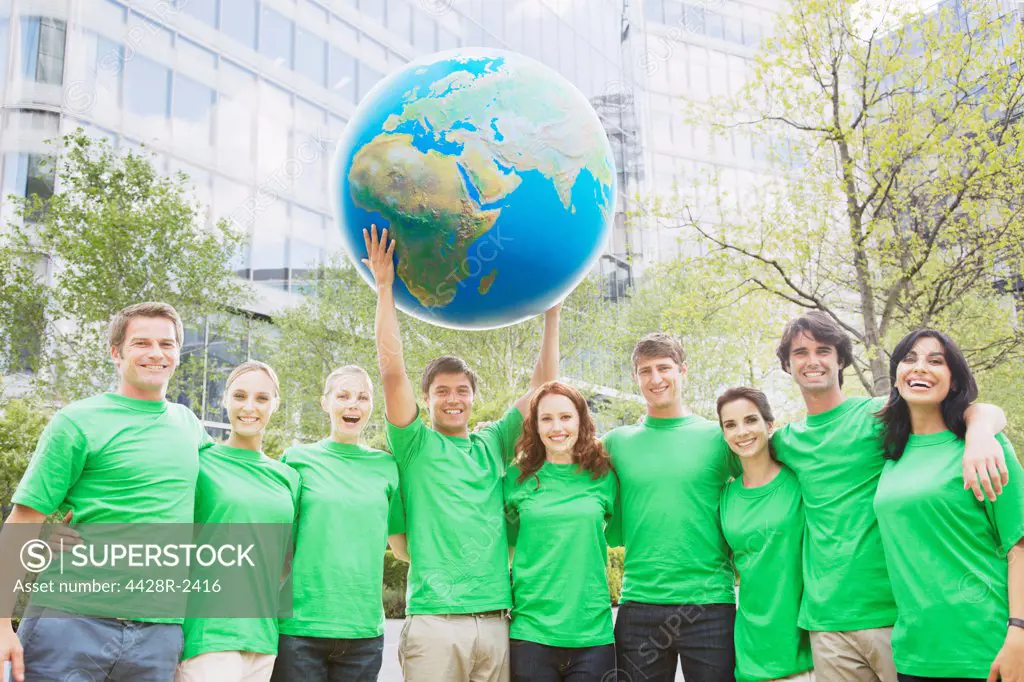Cape Town, South Africa, Portrait of team in green t-shirts lifting globe overhead