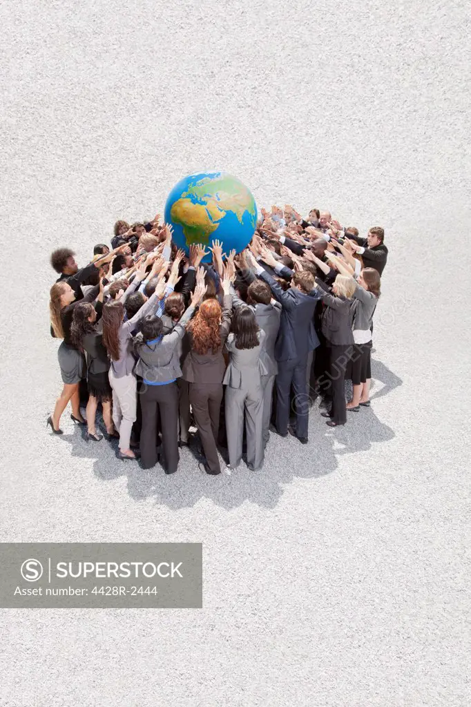 Cape Town, South Africa, Crowd of business people in huddle lifting globe overhead