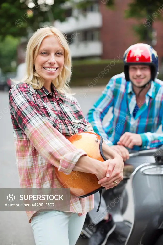 Smiling woman holding scooter helmet,Hamburg, Germany