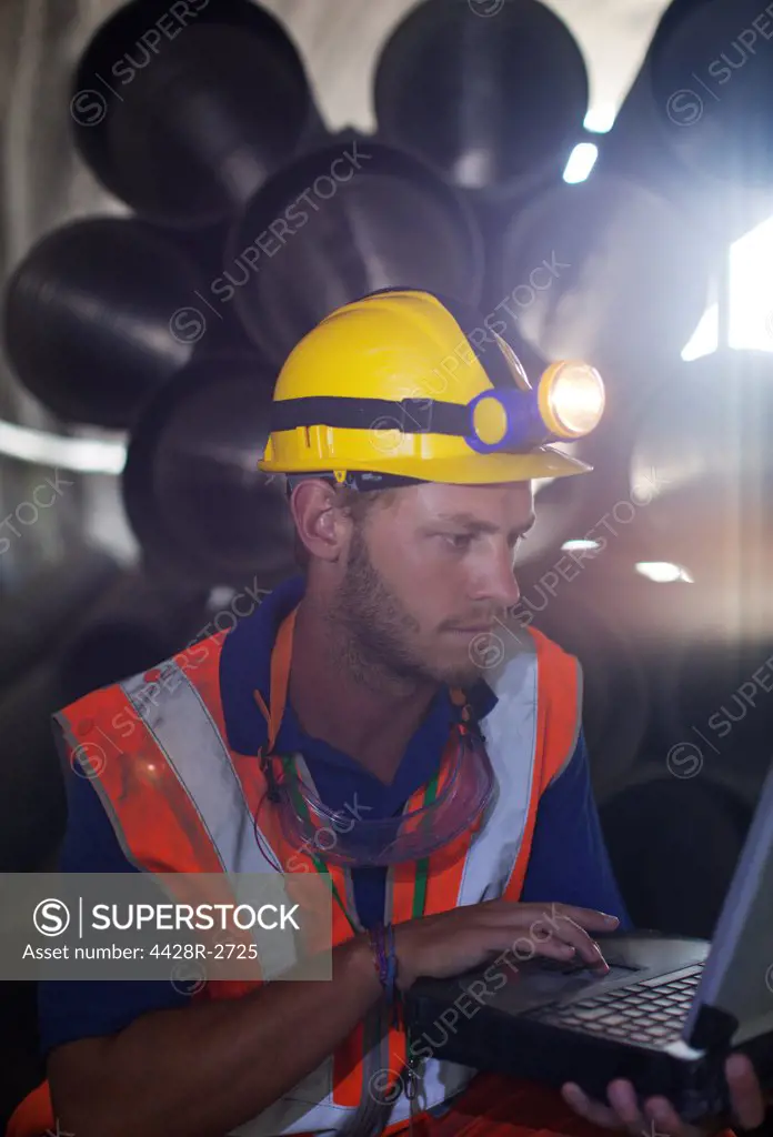 Worker using laptop in tunnel, Spain