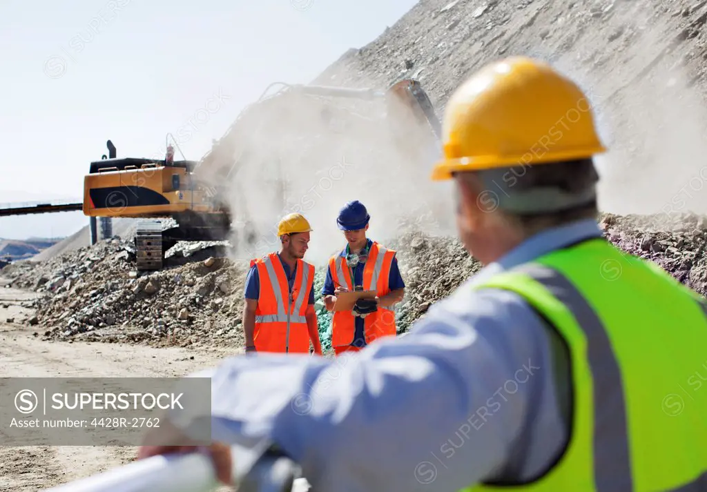 Businessman watching workers in quarry, Spain
