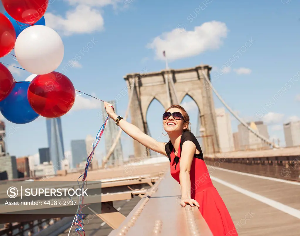 Woman with bunch of balloons on urban bridge,New York