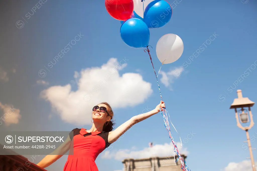 Woman with bunch of balloons on urban bridge,New York