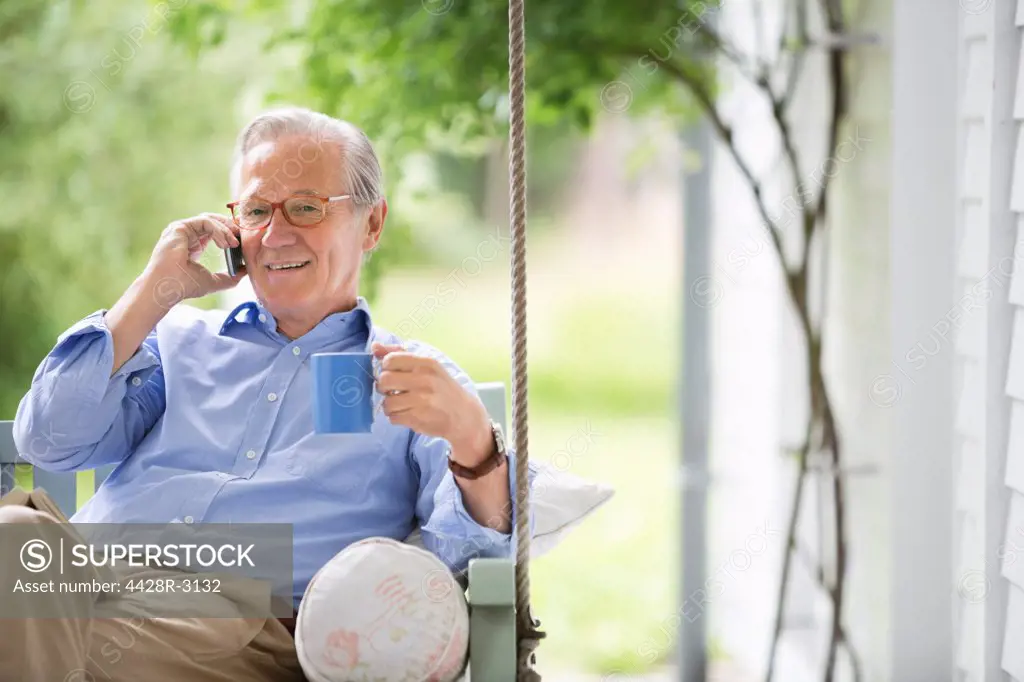 Man talking on cell phone in porch swing,Hamburg, Germany