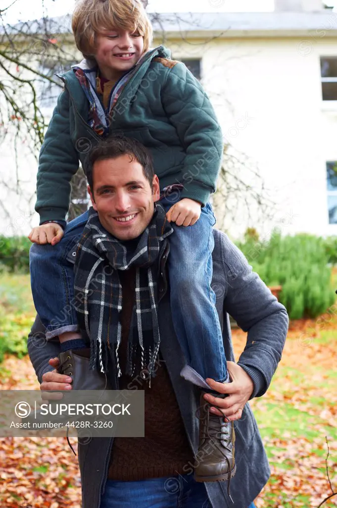 Father carrying son on shoulders outdoors,belmonthouse, UK