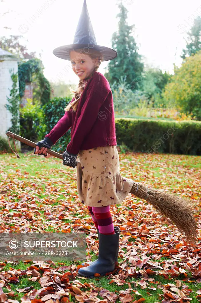 Girl wearing witch costume on broom outdoors,belmonthouse, UK