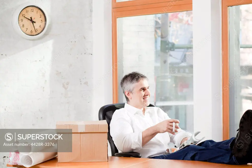 Businessman relaxing at desk in office,Vancouver, Canada