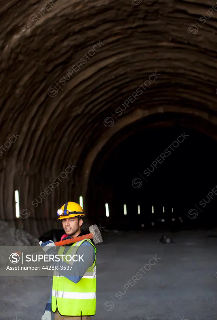 Worker holding sledgehammer in tunnel, Spain