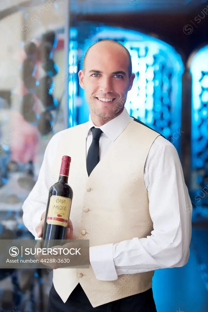 Waiter holding bottle of wine in restaurant, Spain