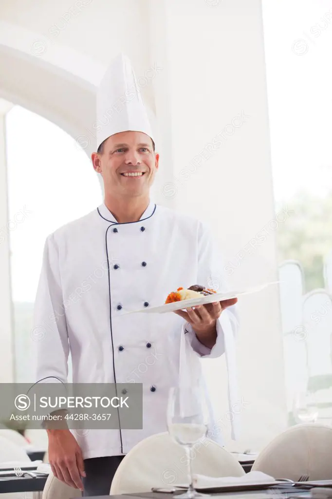 Chef holding plate of food in restaurant, Spain