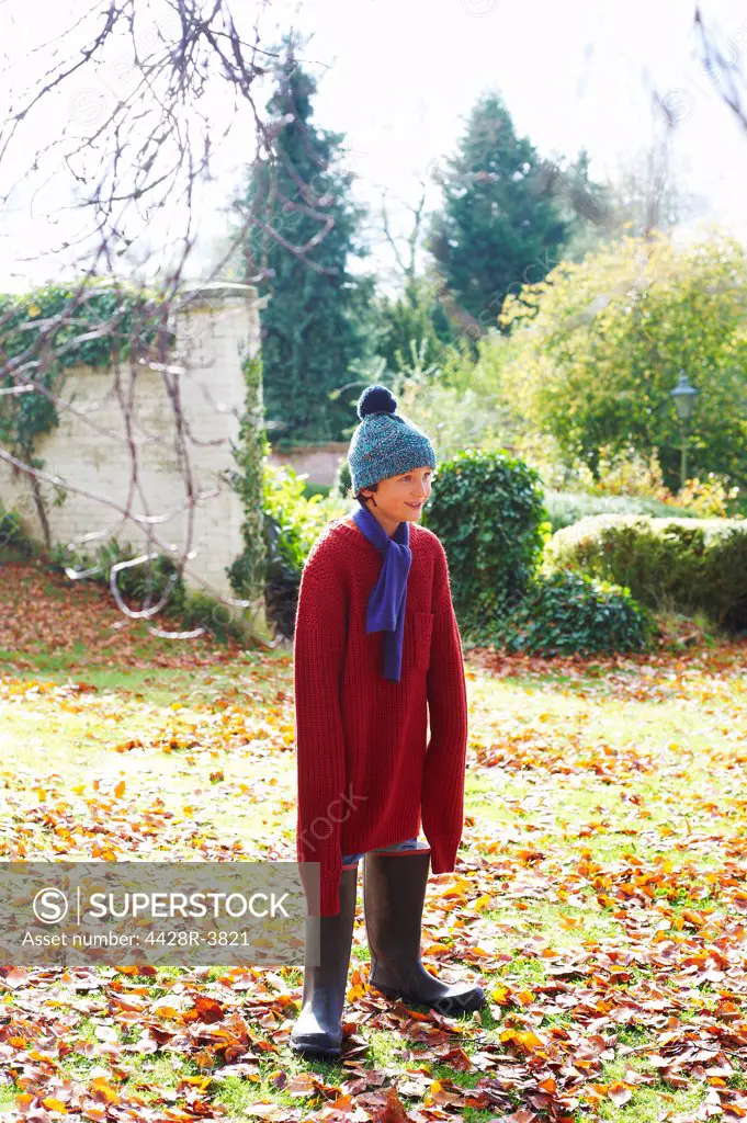 Boy wearing father's sweater and boots outdoors,belmonthouse, UK