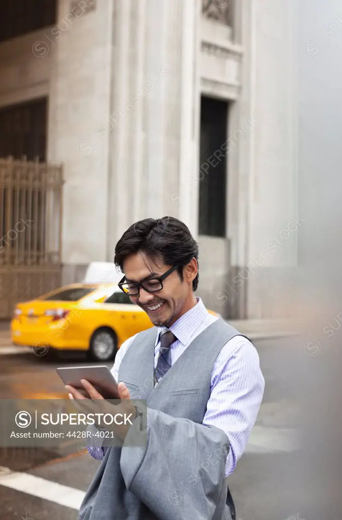 Businessman using tablet computer on city street,New York