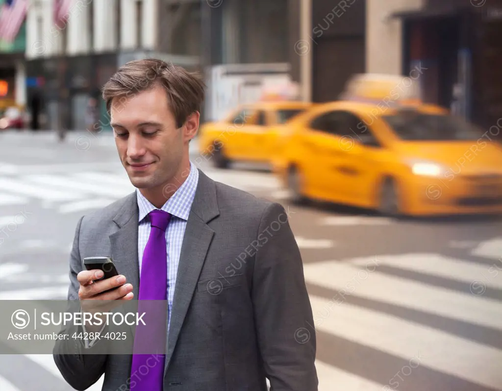 Businessman using cell phone on city street,New York