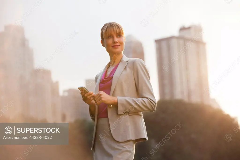 Businesswoman using cell phone in urban park,New York