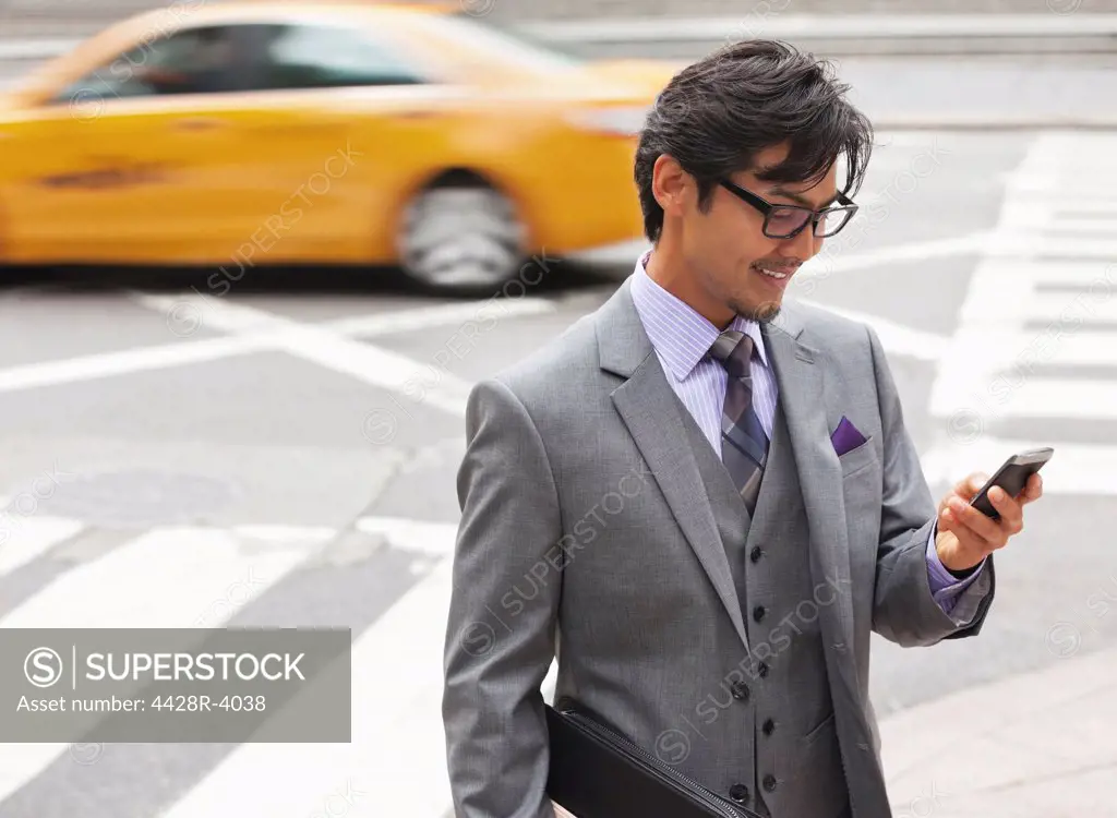Businessman using cell phone on city street,New York