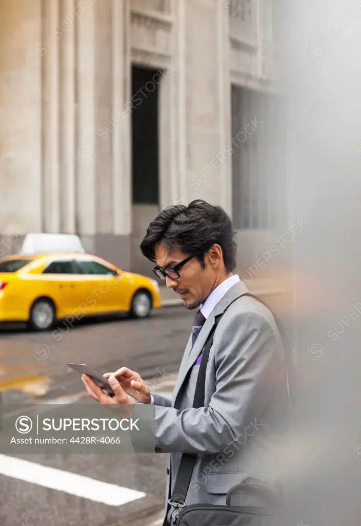 Businessman using tablet computer on city street,New York