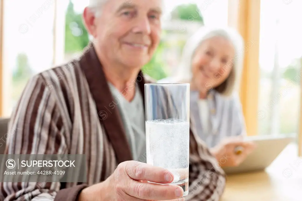 Older man taking medication in water,East Grinstead, UK