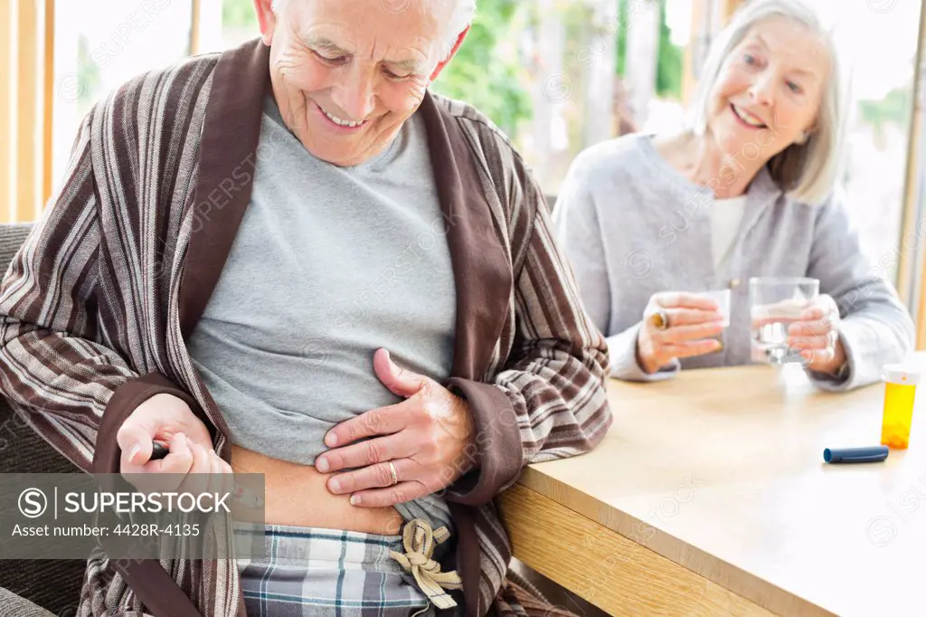 Older man giving himself injection,East Grinstead, UK