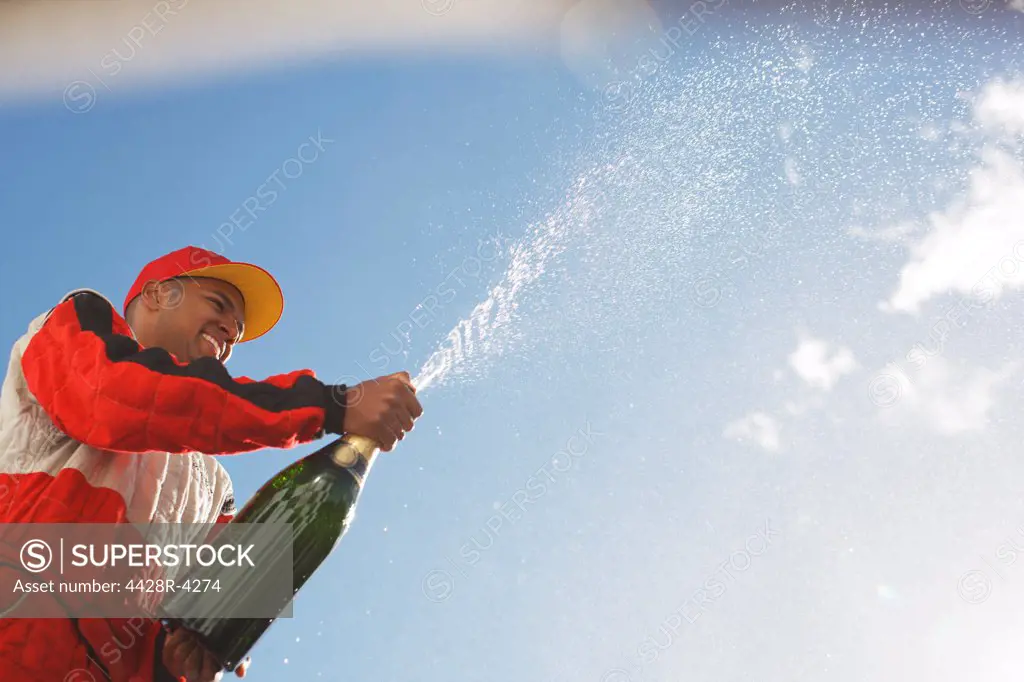 Racer spraying bottle of champagne outdoors,Corby, UK