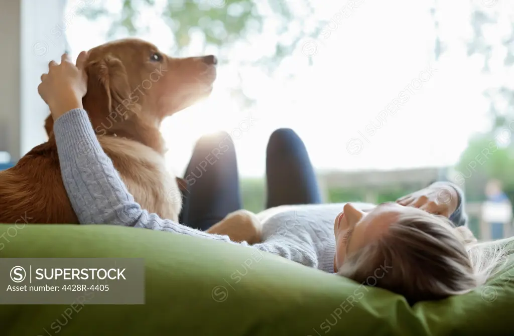 Woman petting dog on bed,Guildford, UK