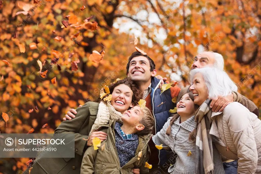 Family playing in autumn leaves in park,London, UK