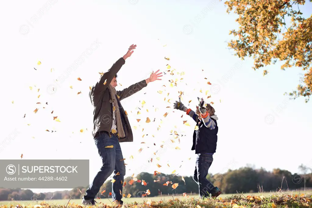 Father and son playing in autumn leaves,London, UK