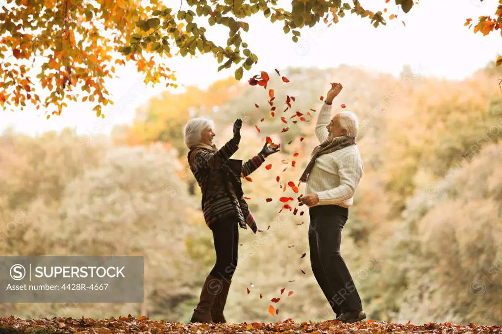 Older couple playing in autumn leaves,London, UK