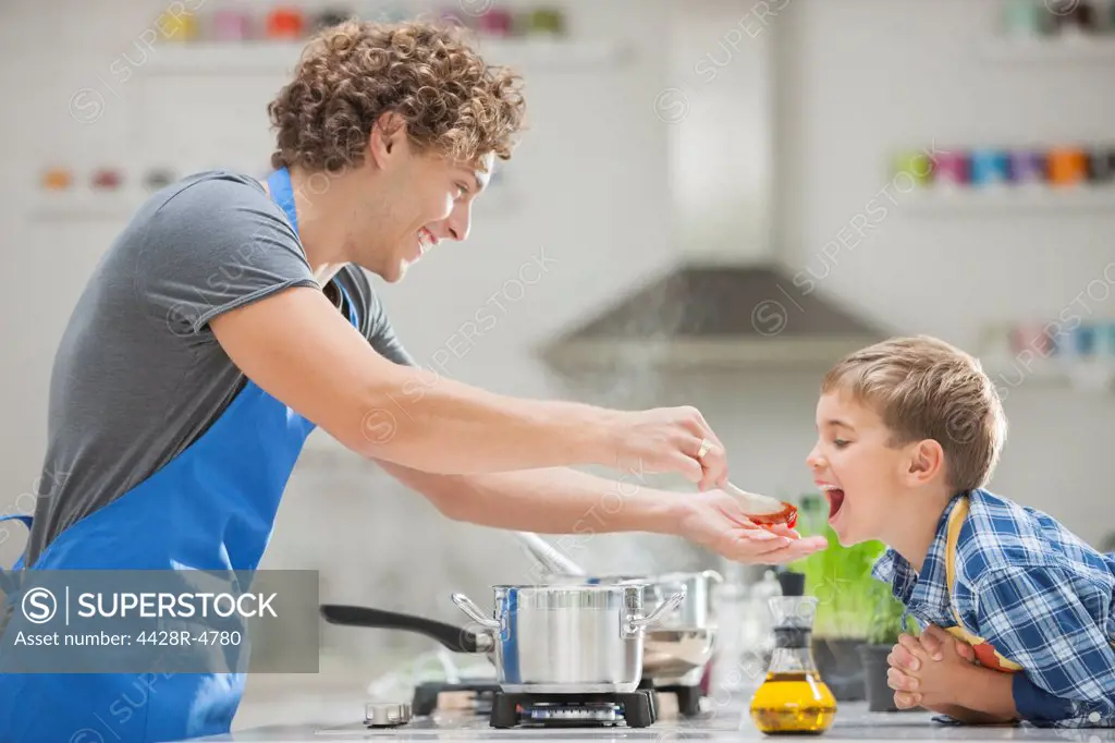 Father and son cooking in kitchen,London, UK