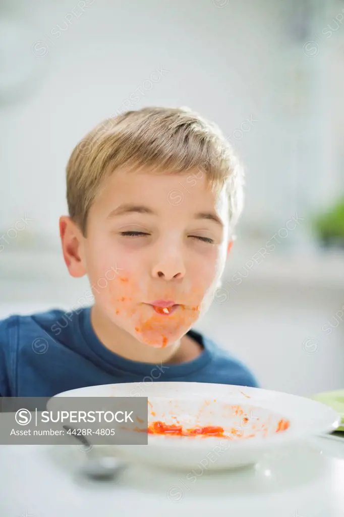 Boy slurping spaghetti at table,London, UK