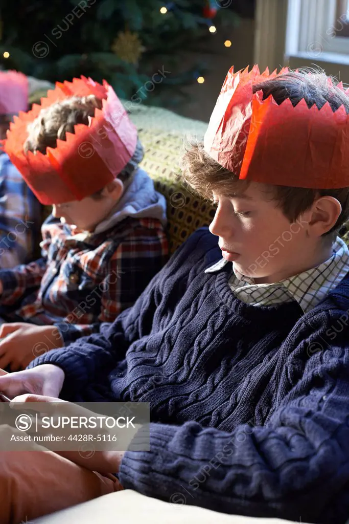 Children in paper crowns relaxing on sofa