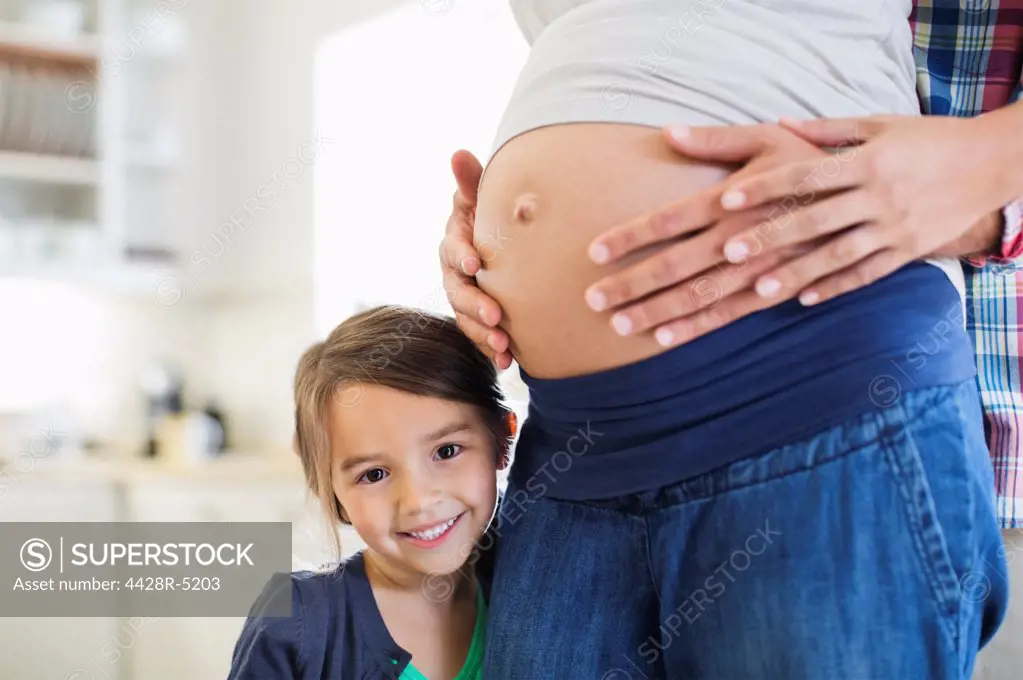 Girl smiling with pregnant mothers belly