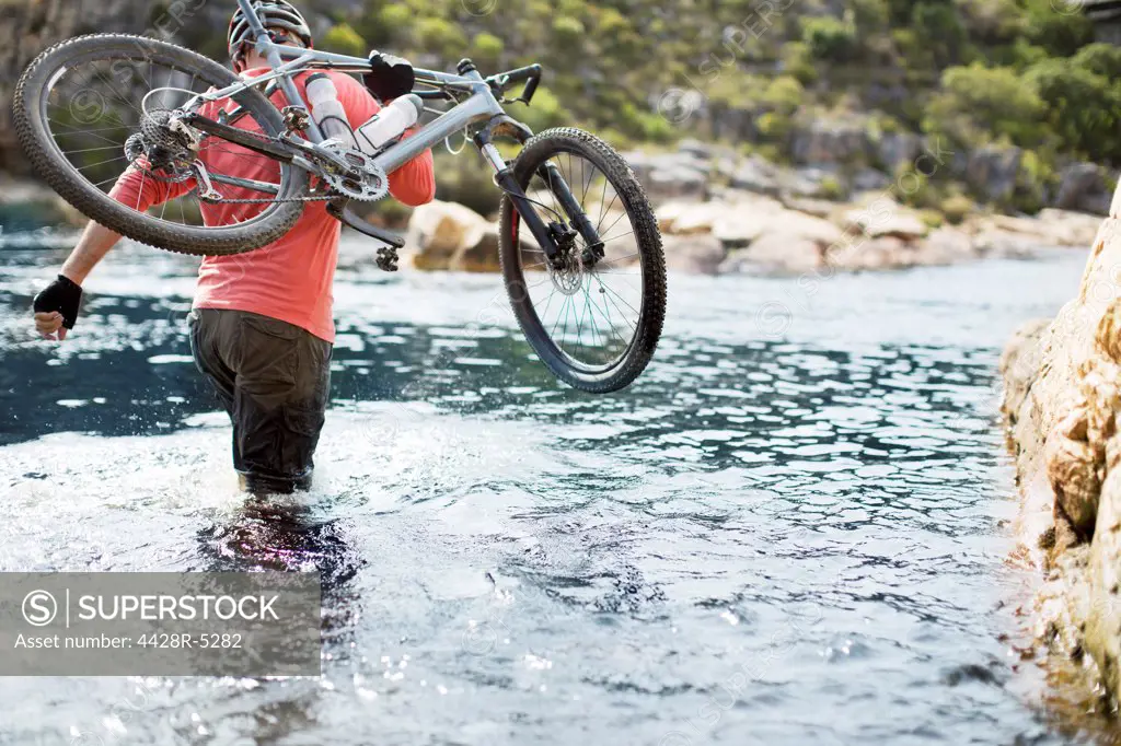 Man carrying mountain bike in river