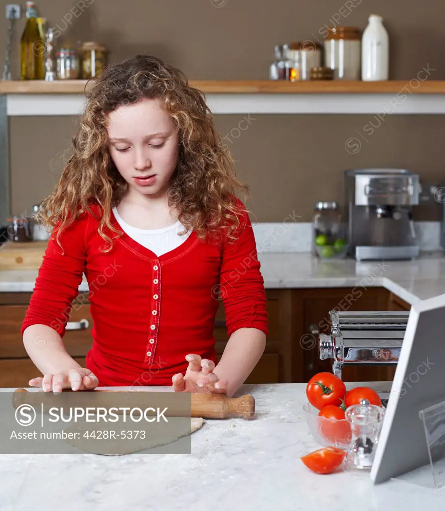 Girl rolling dough in kitchen